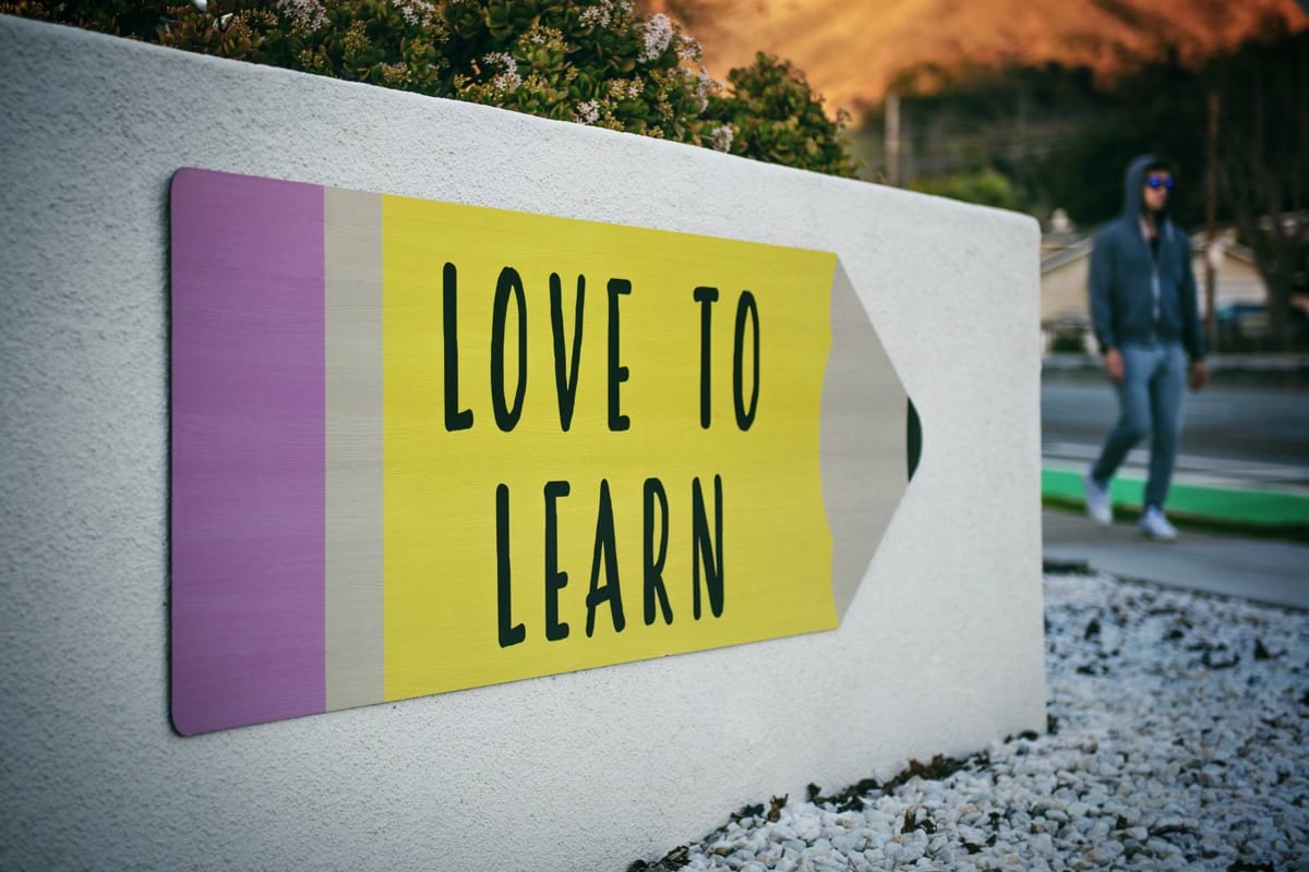 love to learn pencil signage on wall near walking man.jpg