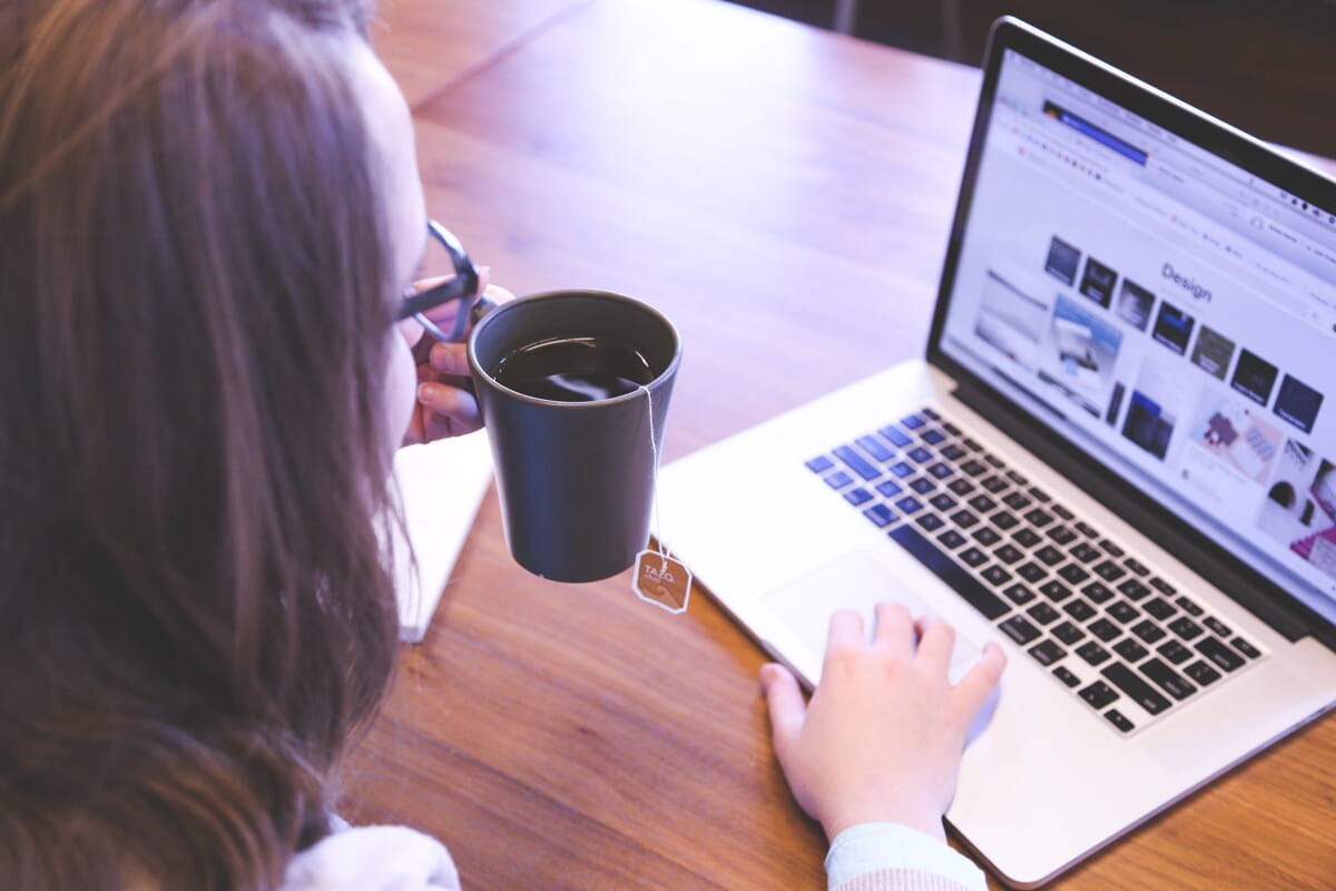 woman holding tea filled mug using MacBook.jpg