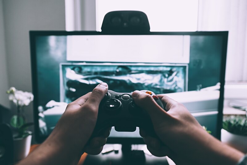 person holding game controller in-front of television